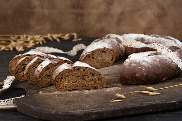 Homemade sourdough sliced bread loaf. Rye ears on the background. Close-up.