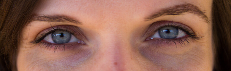Fototapeta na wymiar Close-up image of a young girl's blue eyes. Horizontal banner