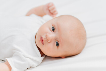  cute baby wearing a white t-shirt on a white sheet. pediatrics