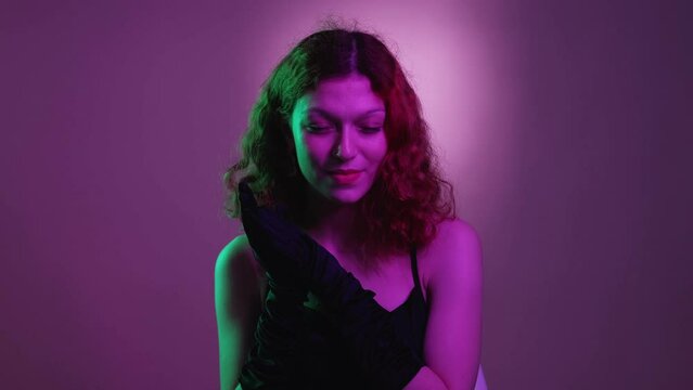 Evil plan. Sneaky woman. Tricky expression. Charming lady with cunning smile rubbing hands in idea scheming in bright purple neon light.