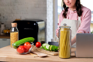 Woman cooking diet food pasta according the tutorial of a online virtual master class.  pasta with...