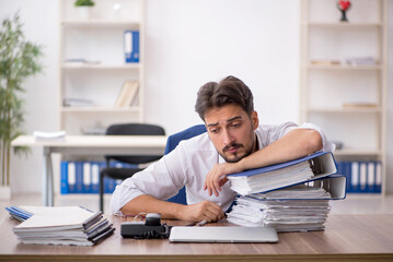Obraz premium Young male employee unhappy with excessive work in the office