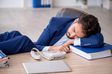 Naklejka premium Young male employee extremely tired in the office