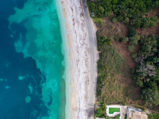 Top-down aerial view of a clean white sandy beach on the shores of a beautiful turquoise sea in corfu Greece