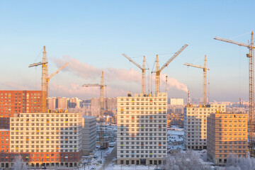 Fototapeta premium Construction of apartment buildings in new Moscow, cranes, skyscraper towers in winter
