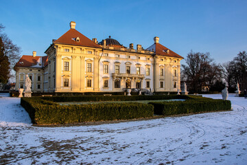 Slavkov Castle in the Czech Republic illuminated by the sun in winter. Snow lies in the park and garden in front of the castle.