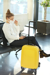 Waiting at the airport.,using smartphone, woman wearing  surgical face mask .