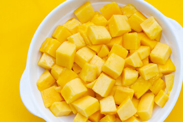 Tropical fruit, Mango cube slices in white bowl on yellow background.