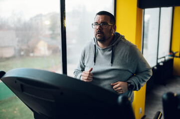 Middle aged man running on a treadmill in the gym