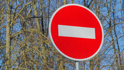 A red round sign warns: entrance forbidden. It is a one way street. In the background a tree. No...