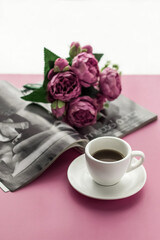 Romantic atmosphere. A cup of coffee and a bouquet of flowers in a magazine on a pink background. Happy birthday banner concept, mother's day, valentine's day. Lifestyle.