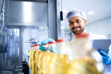 Technologist worker in white lab coat and hairnet controlling in bottling food factory.