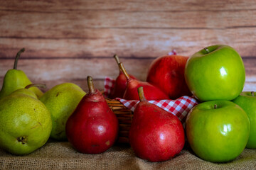 Normal view of some green and red pears and green and red apples in a basket and on a table. Organic and natural products, healthy and wholesome food.