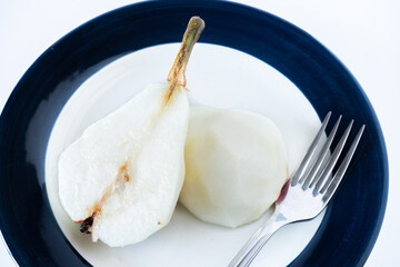 Overhead view of a halved, peeled red battler pear on a plate. Organic and natural products, healthy and wholesome food.