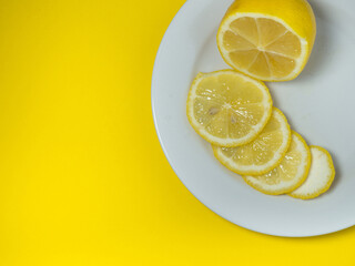 Sliced ​​lemon on a plate on a yellow background. Citrus slices on the table. Bright...