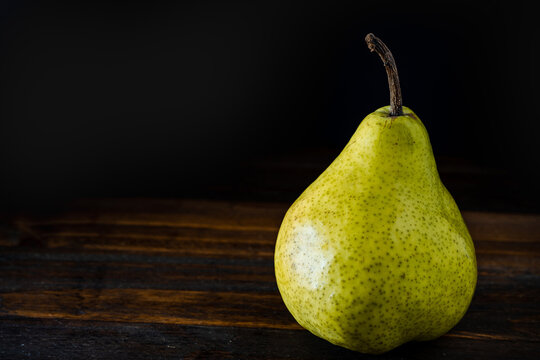 Normal view of a green or packham pear on a table. Dark background. Organic and natural products, healthy and wholesome food.