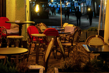  Rattan chairs and wooden tables of sidewalk cafe at night
