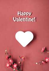 Happy Valentine text. Valentines day simple minimal background. Plum flowers, twigs with plum blossoms on red paper.