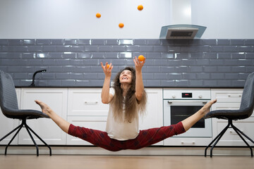 Young, flexible woman doing stretching during Breakfast in the kitchen. Healthy lifestyle and yoga concept