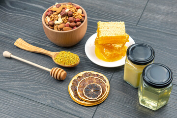 assortment of nuts and assorted dried citrus fruits and fresh floral honeycomb honey and pollen on kitchen wooden board. useful vitamin food for the human body