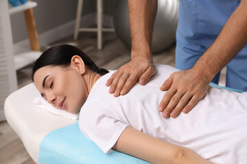 Fototapeta na wymiar Orthopedist massaging young woman's back in clinic, closeup. Scoliosis treatment