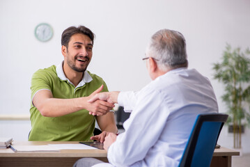 Young man visiting old male doctor