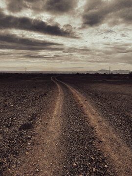 dark empty desert mountain trail adventure evening dusk horizon silhouette sepia dirt road moody landscape background