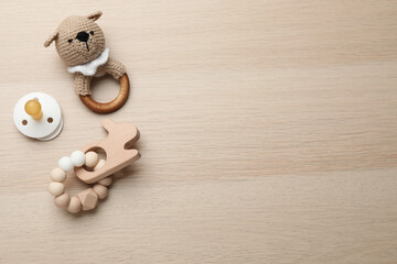 Cute baby toys and pacifier on wooden background, flat lay. Space for text