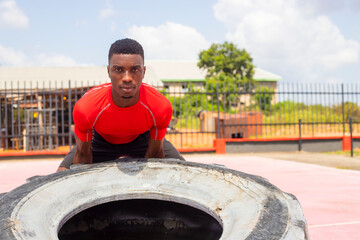 Fototapeta na wymiar Athletic man lifting a large gym tire in gym