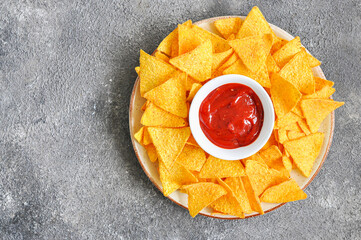 Corn chips with ketchup in a plate on a gray background. Top view. - 485441916