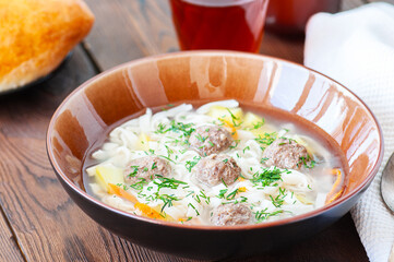 Homemade meatballs soup with noodles on a wooden background. Close up.