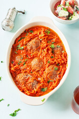 Homemade meat cutlets with tomato sauce in a baking dish on a blue background.