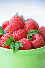 Fresh ripe raspberries in a green bowl on a wooden background. Close up.