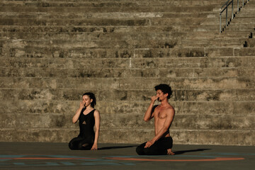 Couple doing yoga fitness exercises sport in the streets with open arms, stairs background....