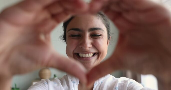 Happy smiling Indian woman joining fingers showing heart symbol to camera, close up. Blogger record video, share with subscribers love, warmth, positive emotions. Donation, medicine, insurance concept