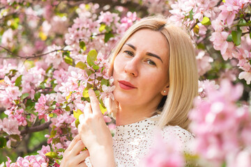 Young woman among the blossoming trees. Spring nature park or garden, flowering trees. Concept spring woman health