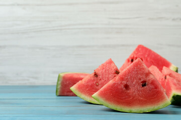 Slices of tasty ripe watermelon on turquoise wooden table, space for text