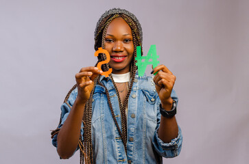 beautiful black lady smiling as she holds naira and dollar symbols towards each other