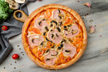 Pizza with ham and mushrooms on grey wooden table top view