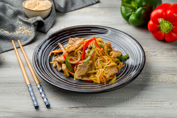 wok noodles with pork and vegetables on grey wooden table