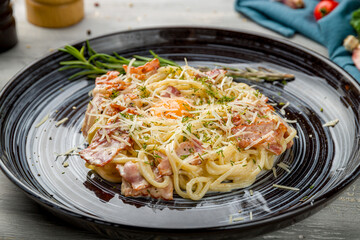 Spaghetti Carbonara with bacon and egg on grey wooden table macro close up
