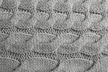 Grey knitted fabric with beautiful pattern as background, top view