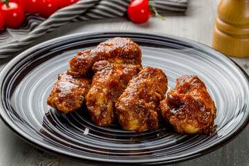 Buffalo chicken wings on grey plate on grey wooden table macro close up