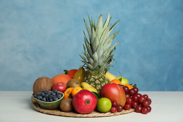 Assortment of fresh exotic fruits on white wooden table against light blue background