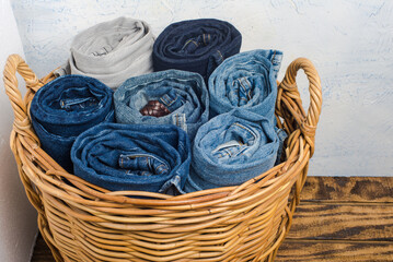 Fototapeta na wymiar lot of jeans are packed in a wicker basket against a white wall.
