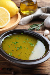 Bowl with lemon sauce on wooden table, closeup. Delicious salad dressing