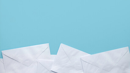 A stack of white envelopes on blue background with copy space. - obrazy, fototapety, plakaty