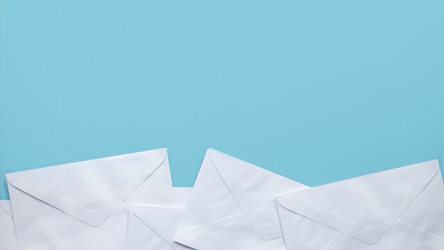 A stack of white envelopes on blue background with copy space.