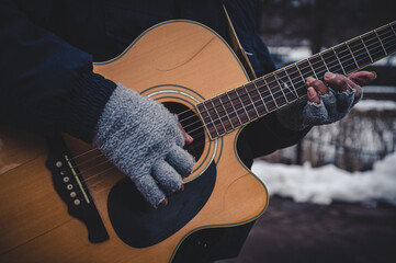 Weathered hands playing beat up guitar 