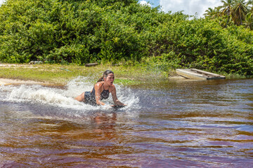 Mulher deslizando numa prancha sob agua num rio